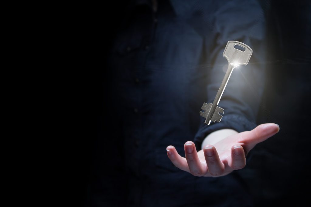 business woman holding shining key in a dark